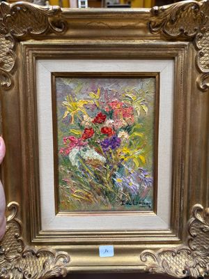 une personne tenant un tableau représentant des fleurs dans un cadre doré