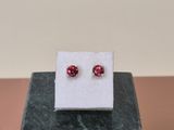 a pair of red cubicge earrings sitting on top of a marble block