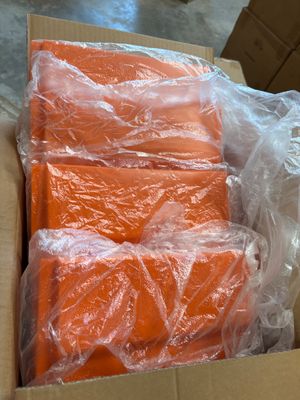 une boîte remplie de morceaux de plastique orange posée par terre