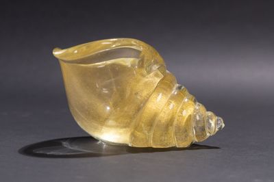 une image représentant un coquillage en verre jaune posé sur une surface noire