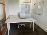 a white desk with a white chair and a map on the wall