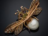 a close up of a dragonfly broochle with pearls on a black surface