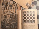 deux livres posés sur une table où se trouvent des pièces d'échecs
