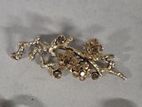a gold brooch with flowers and leaves on it