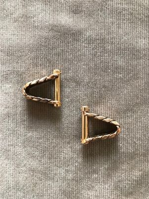 une paire de boucles d'oreilles en or posées sur une surface grise