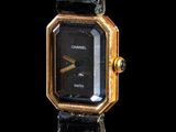 une image représentant une montre-bracelet noire et dorée sur fond noir