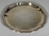 un plat en argent ancien posé sur une table blanche, sur fond blanc
