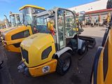yellow construction vehicles parked in a parking lot next to a building