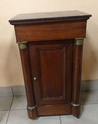 a small wooden cabinet with a black top on a tiled floor