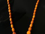 a close up of a necklace with orange beads on a black surface