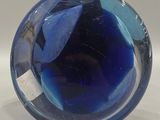 a blue glass ball sitting on a white surface