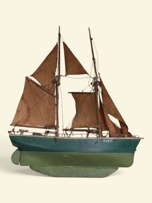 une petite maquette de voilier posée sur une surface blanche