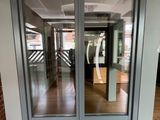 une photo représentant une double porte vitrée sur laquelle est apposée une pancarte jaune