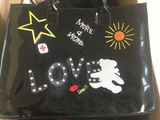 Quelqu'un tient un sac noir sur lequel est dessiné un ours en peluche.