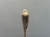 une cuillère en argent avec un manche en forme de cœur, posée sur une table