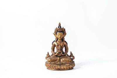 une statue en or représentant un Bouddha assis sur un socle blanc