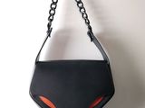 Le sac à main noir et orange est accroché au mur.