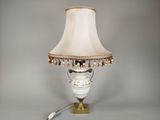 une lampe posée sur une table, avec un abat-jour blanc