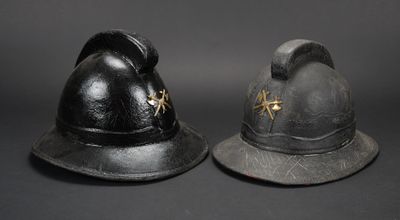 une paire de casques de pompier anciens exposés sur fond noir