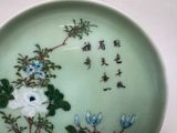 a green plate with flowers and chinese writing on it