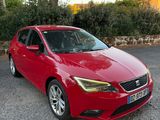 une voiture rouge garée sur un parking, près d'un arbre