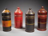trois bidons rouges et noirs sont alignés sur un fond gris