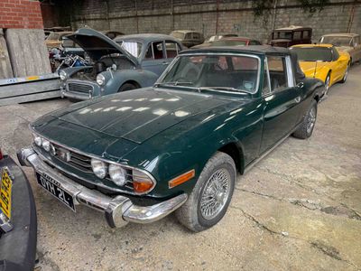 a green car parked in a garage next to other cars