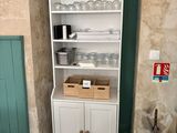 une armoire blanche sur laquelle sont posés des objets en verre, dans un coin de la pièce