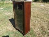 une grande armoire en bois avec une porte vitrée, posée dans l'herbe
