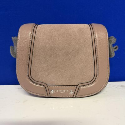 a tan leather purse with a metal handle on a white table