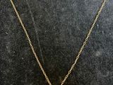 a gold necklace with a coin on a chain
