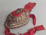 an old hat with a red ribbon around it on a white surface
