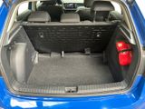 the back of a blue car with its trunk open and a red bag in the trunk