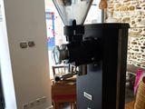 a coffee grinder sitting on a table in front of a stone wall