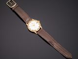 a gold wrist watch with a brown leather strap and white dial