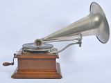 a silver gramphone on a wooden stand on a white background