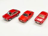 trois petites voitures rouges posées les unes à côté des autres sur une surface blanche