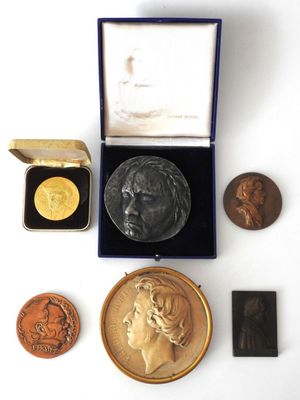 an assortment of gold and silver medals including a bust of a woman