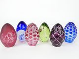 six glass easter eggs lined up in a row on a white surface