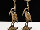 une paire de bougeoirs anciens en laiton ornés d'oiseaux sur le dessus