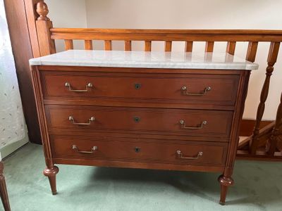 a dresser with a marble top in the corner of a room
