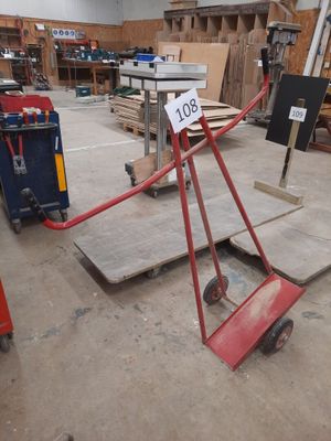 a red hand truck with a sign on it in a warehouse