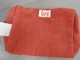 an orange corded bag with a white label on it