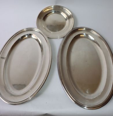 trois plateaux ovales en argent posés sur un plateau de table blanc