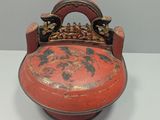 an old red vase with a handle on a white table