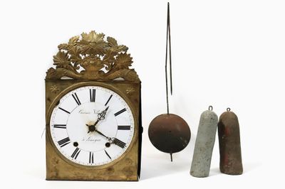 une petite horloge avec un pendule et une cloche à côté