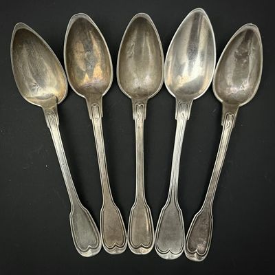 six cuillères en argent sont alignées sur une surface noire