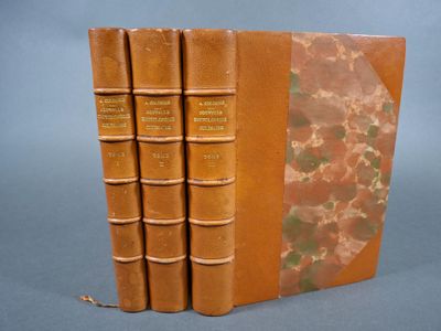 trois livres marron empilés les uns sur les autres sur une table