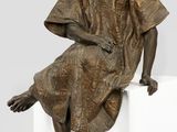 statue en bronze représentant une femme assise sur un cube blanc
