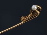 a close up of a gold stick with a pearl in it